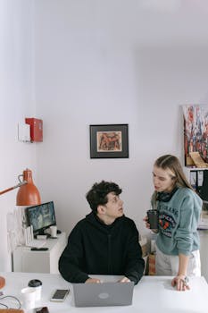 Two young professionals discussing a project in a modern office, fostering teamwork and creativity.