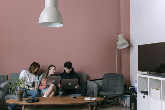 Adults discussing and working on laptops in a cozy living room setting.