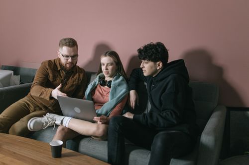 Free Young team discussing project on laptop in cozy office setting. Stock Photo