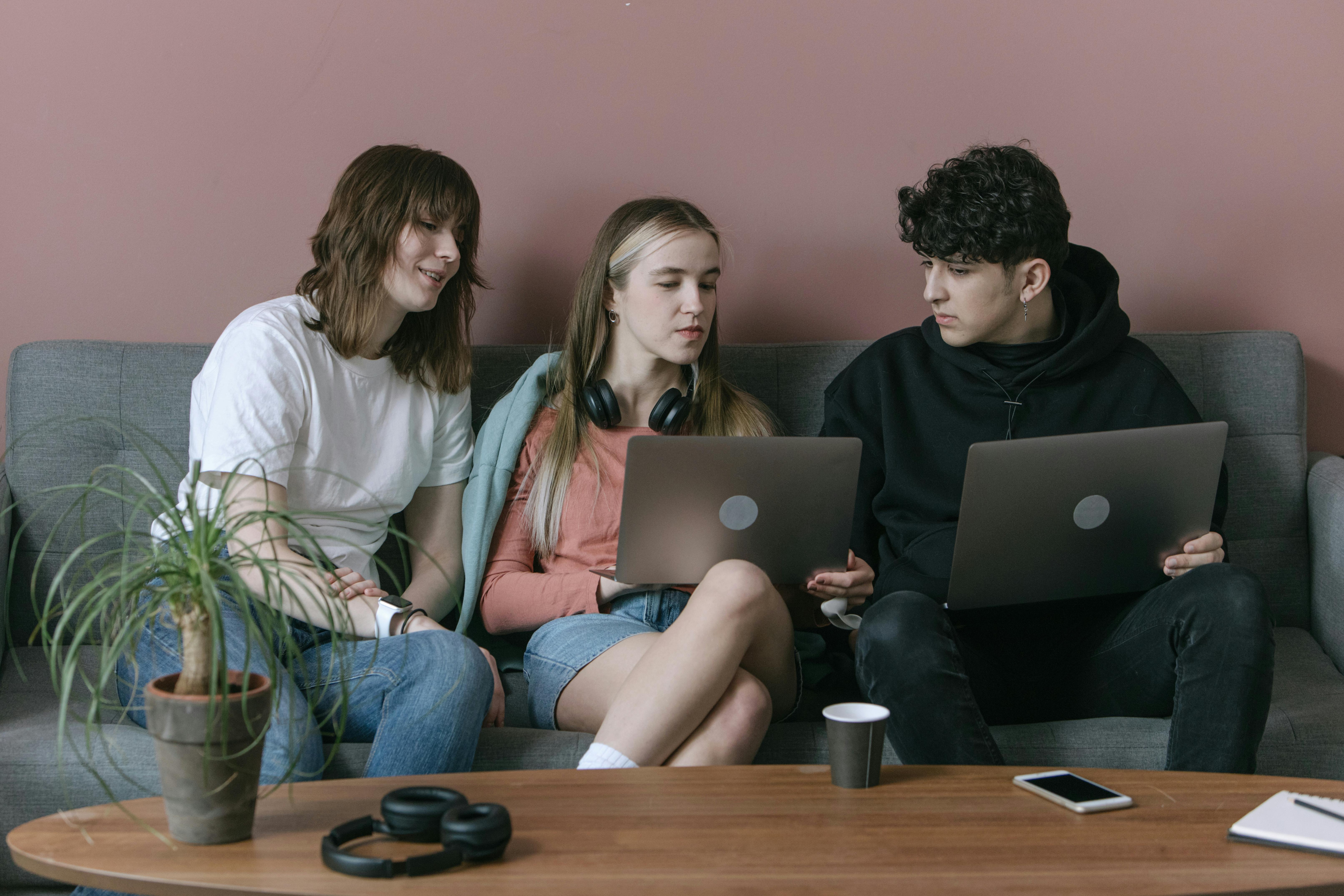 woman in white long sleeve shirt sitting beside woman in blue denim jeans using macbook