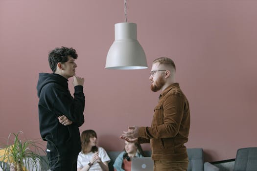 A group of young professionals engaging in a casual office meeting with a modern and stylish backdrop.