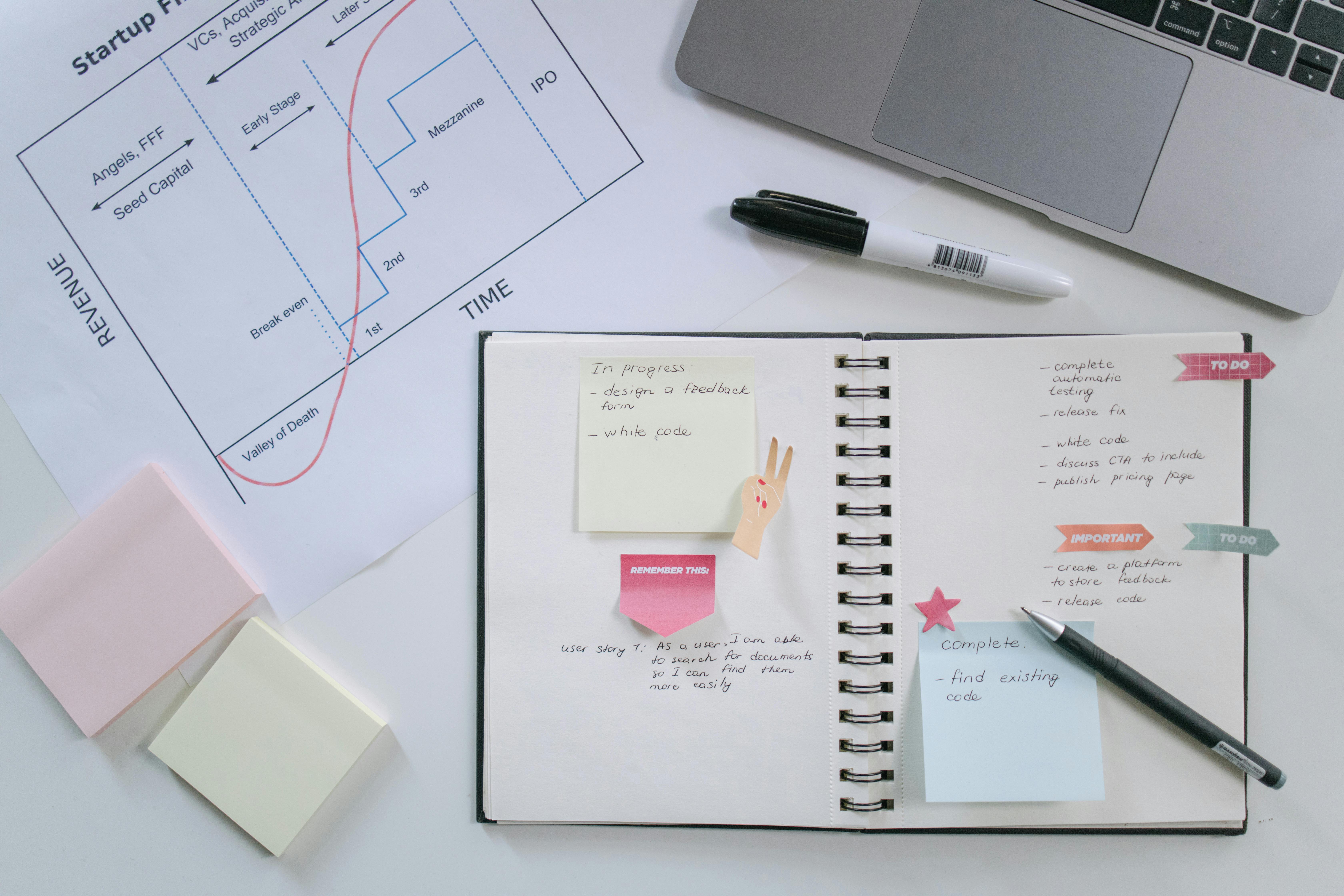 high angle shot of a notebook and a pen beside a laptop