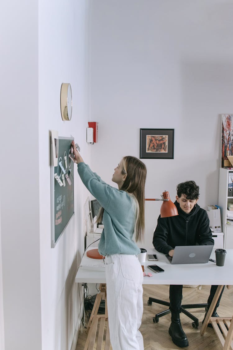 A Woman Sticking Notes On The Board