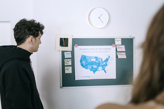Young professionals discussing a map of US tech startups in a modern office setting.