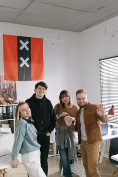 Smiling coworkers in an office pose in front of the Amsterdam flag, showing team spirit.