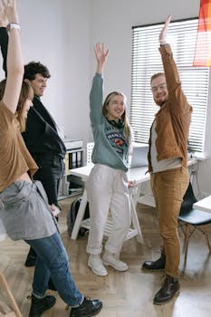 A joyful, diverse group of young adults celebrating in an office space, embodying teamwork and success.