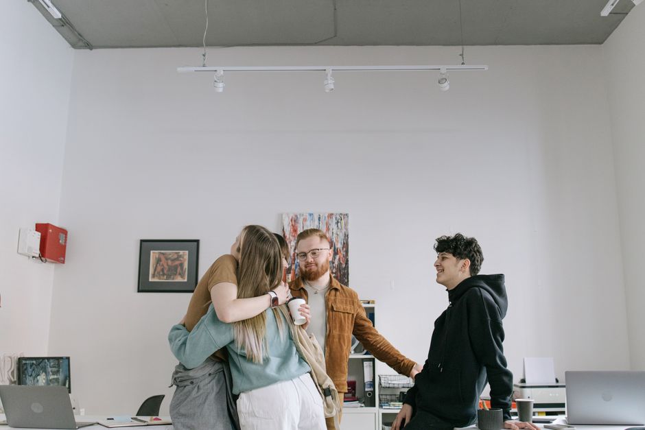 Un grupo de jóvenes profesionales abrazándose en un entorno de oficina moderno, mostrando trabajo en equipo y camaradería.