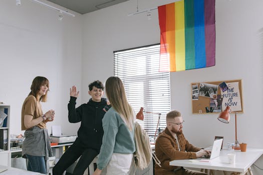 Young professionals working together in a creative office space with pride flag symbolizing inclusivity.