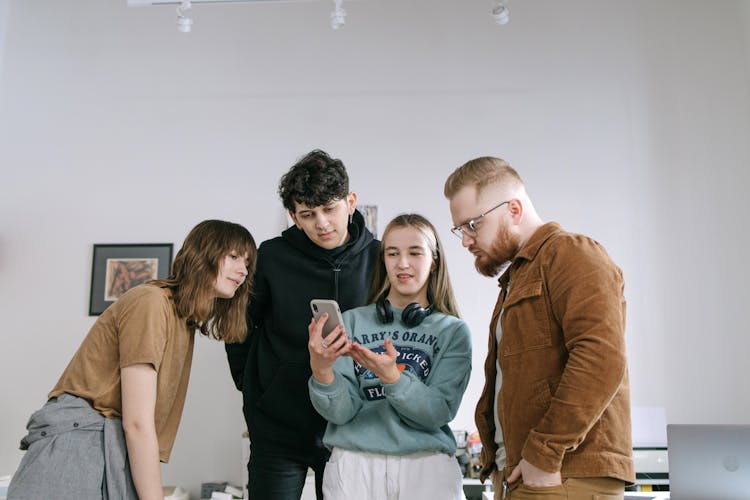 Group Of Friends Standing And Looking On A Smartphone