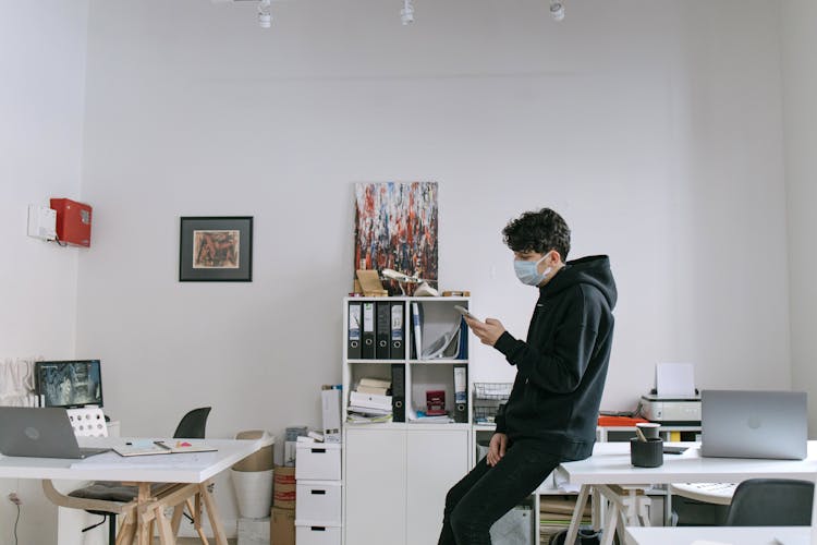 Man Wearing Facemask Using Smartphone In Office