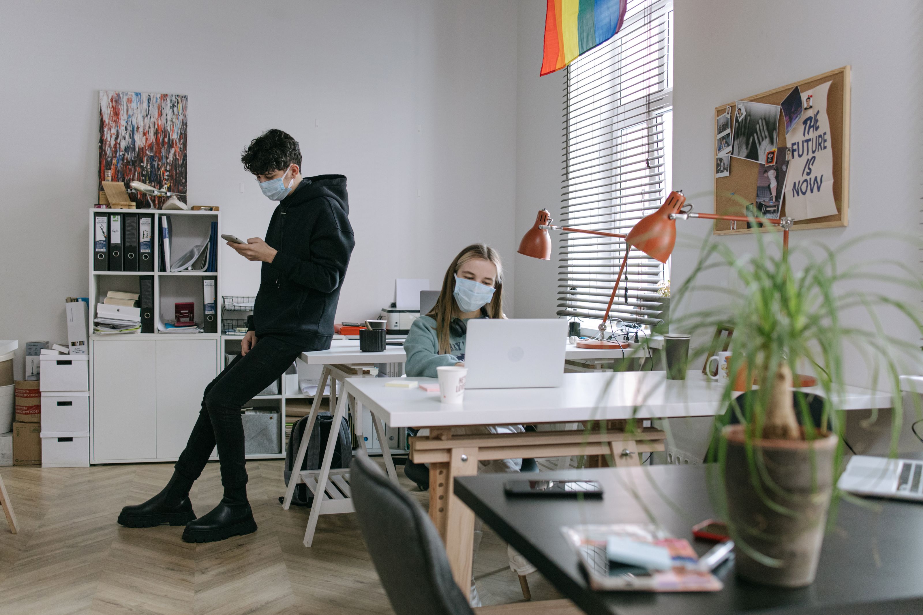 Two masked individuals working in a contemporary office setting, embracing the new normal.
