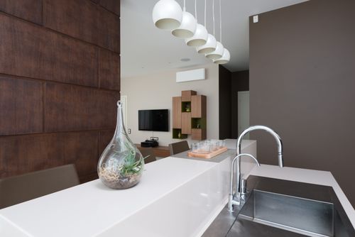 Free Decorative glass vase placed on white counter near sink with faucet in light modern apartment against decorated wall with TV Stock Photo