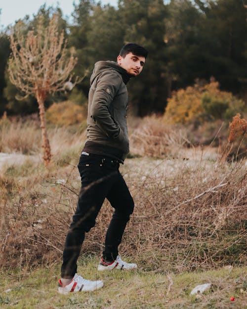 Free Man in Black Hoodie Jacket and Black Pants Standing on Grassland Stock Photo