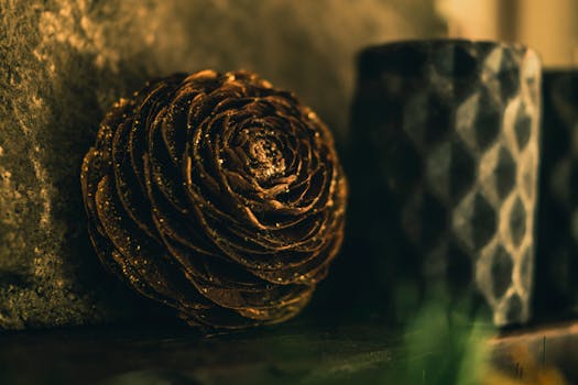 特写照片中，闪闪发光的金色松果装饰品旁摆放着一支纹理蜡烛