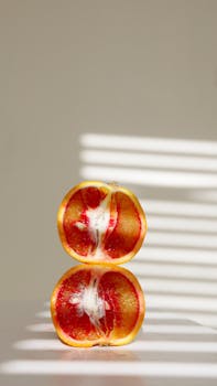A sliced blood orange resting on a sunlit surface, showcasing its vibrant colors and textures.