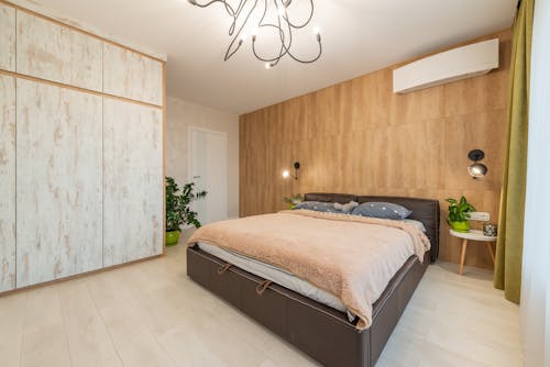 Large comfortable bed placed against wooden wall in spacious modern apartment in daytime