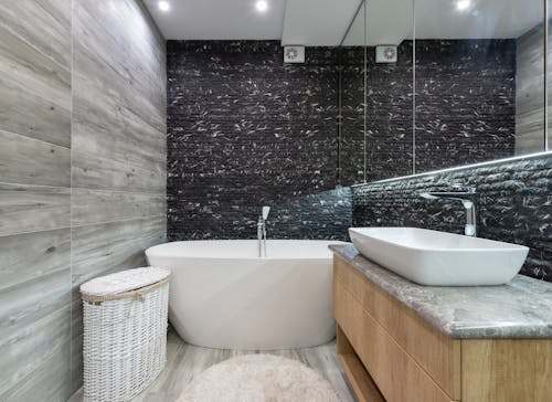 White Ceramic Bathtub Near  Black Textured Wall