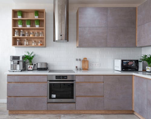 Interior of modern kitchen with white tiled walls and stylish furniture in contemporary apartment in daylight