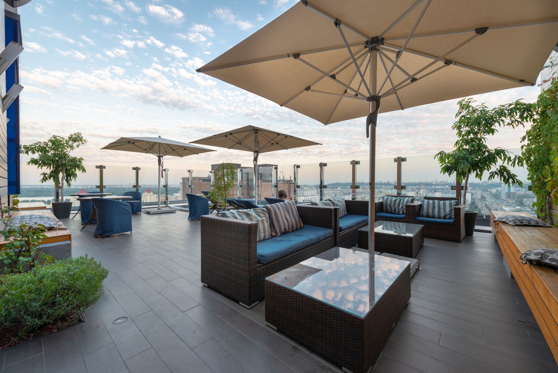 Modern lounge zone with comfortable sofas and tables under umbrellas on terrace in daytime