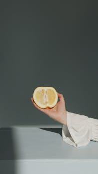 A fresh lemon half held in a hand with a dark background, showcasing its juicy and vibrant nature.