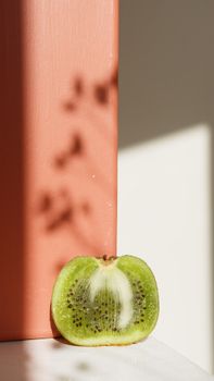 Close-up of a fresh kiwi slice with artistic shadows, highlighting its vibrant green color and seeds.