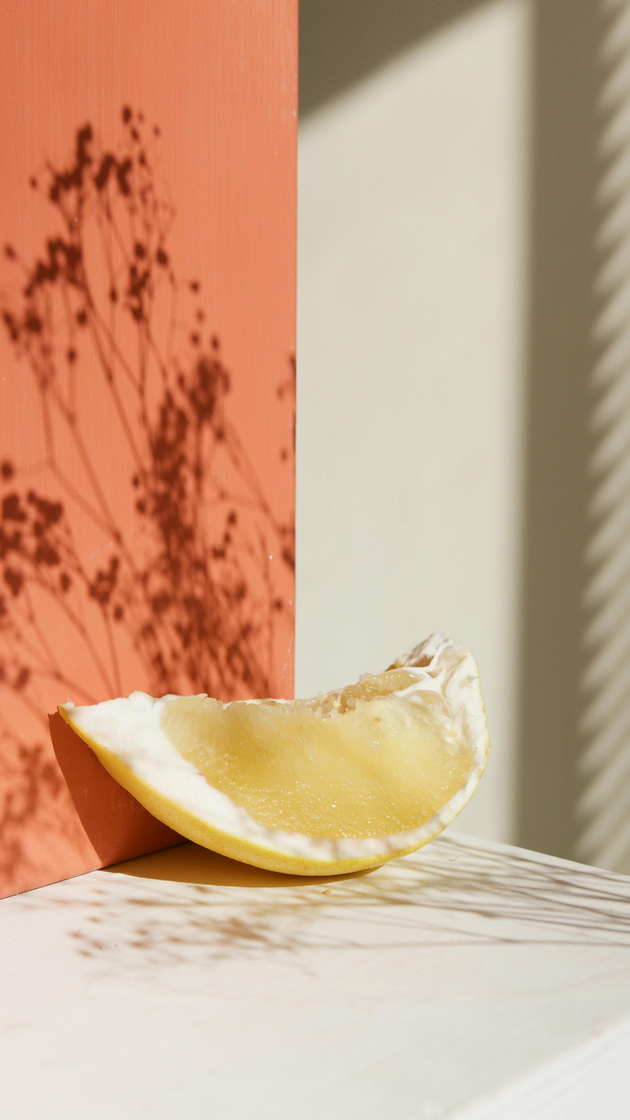 Artistic close-up of a freshly sliced lemon against a pastel background, bathed in sunlight.