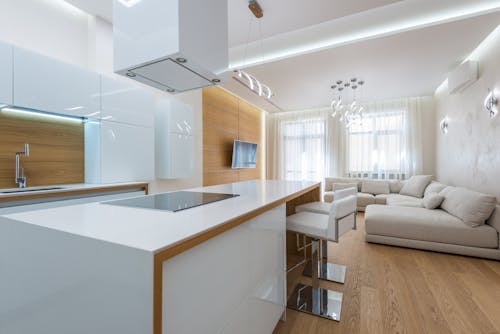 White kitchen counter with stove placed in kitchen zone against living room in contemporary apartment