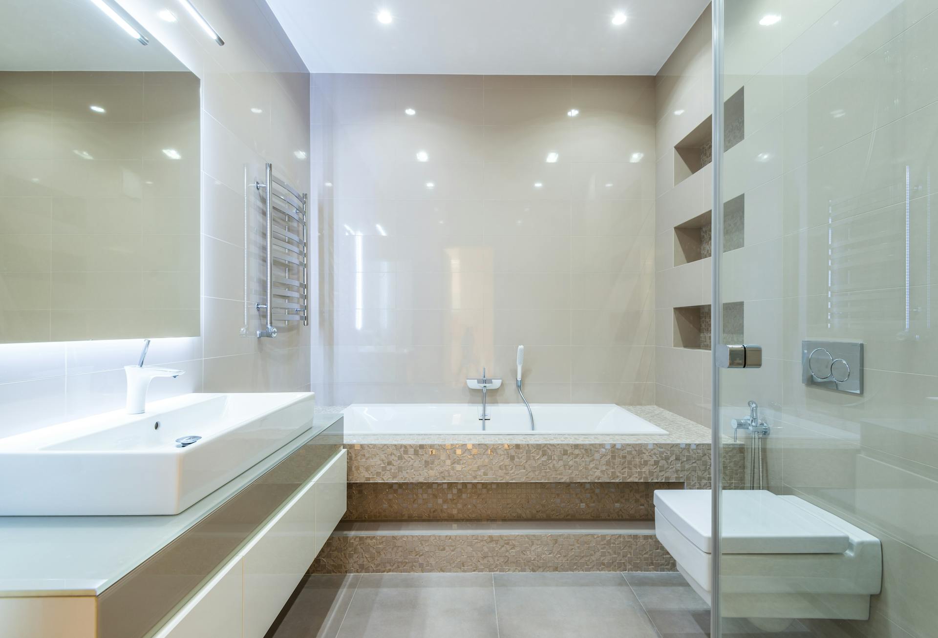 Empty spacious clean bathroom with tiled walls and light furniture in modern flat