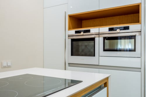 Interior of contemporary light kitchen with white ovens and clean new stove in modern apartment