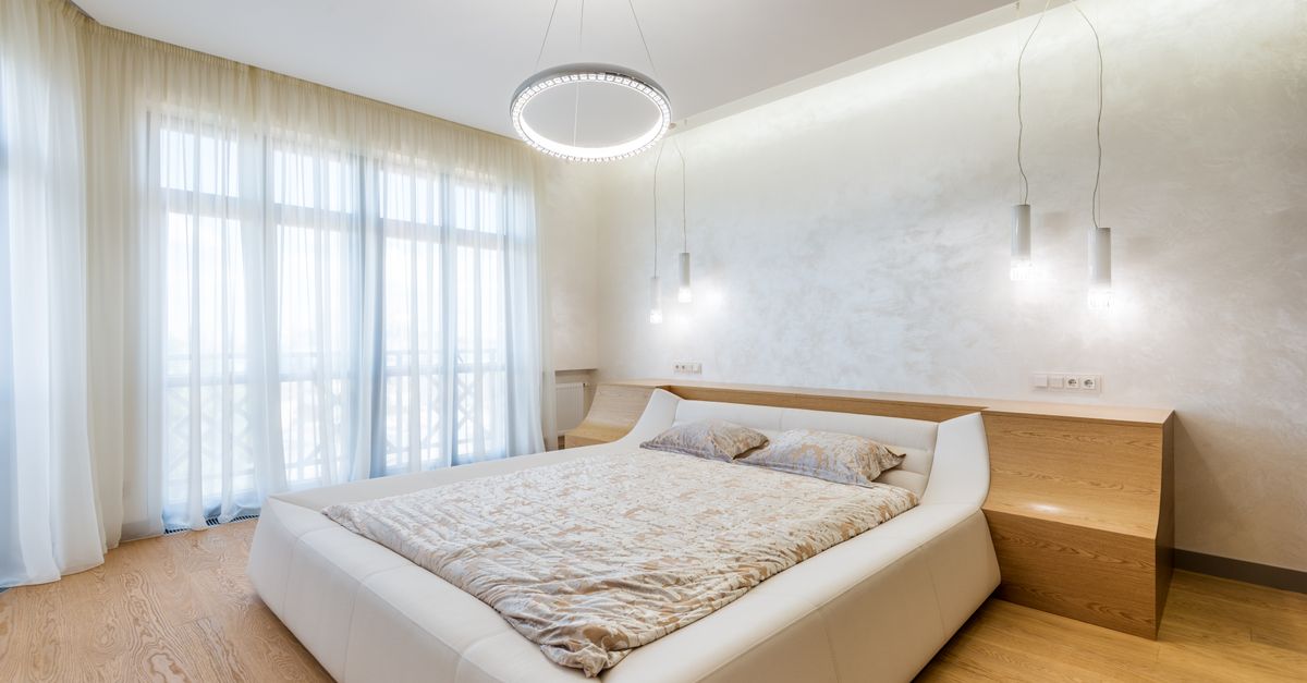 Clean, minimalist bedroom with a tidy bed and empty surfaces in a light room