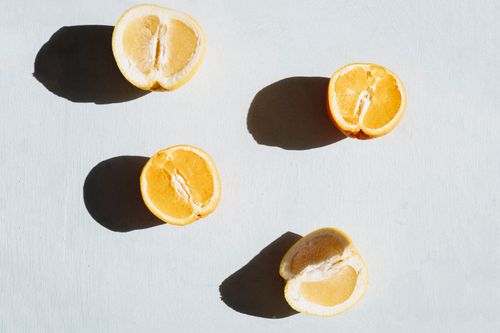 Free Artistic photo of halved citrus fruits casting shadows on a pale surface. Stock Photo