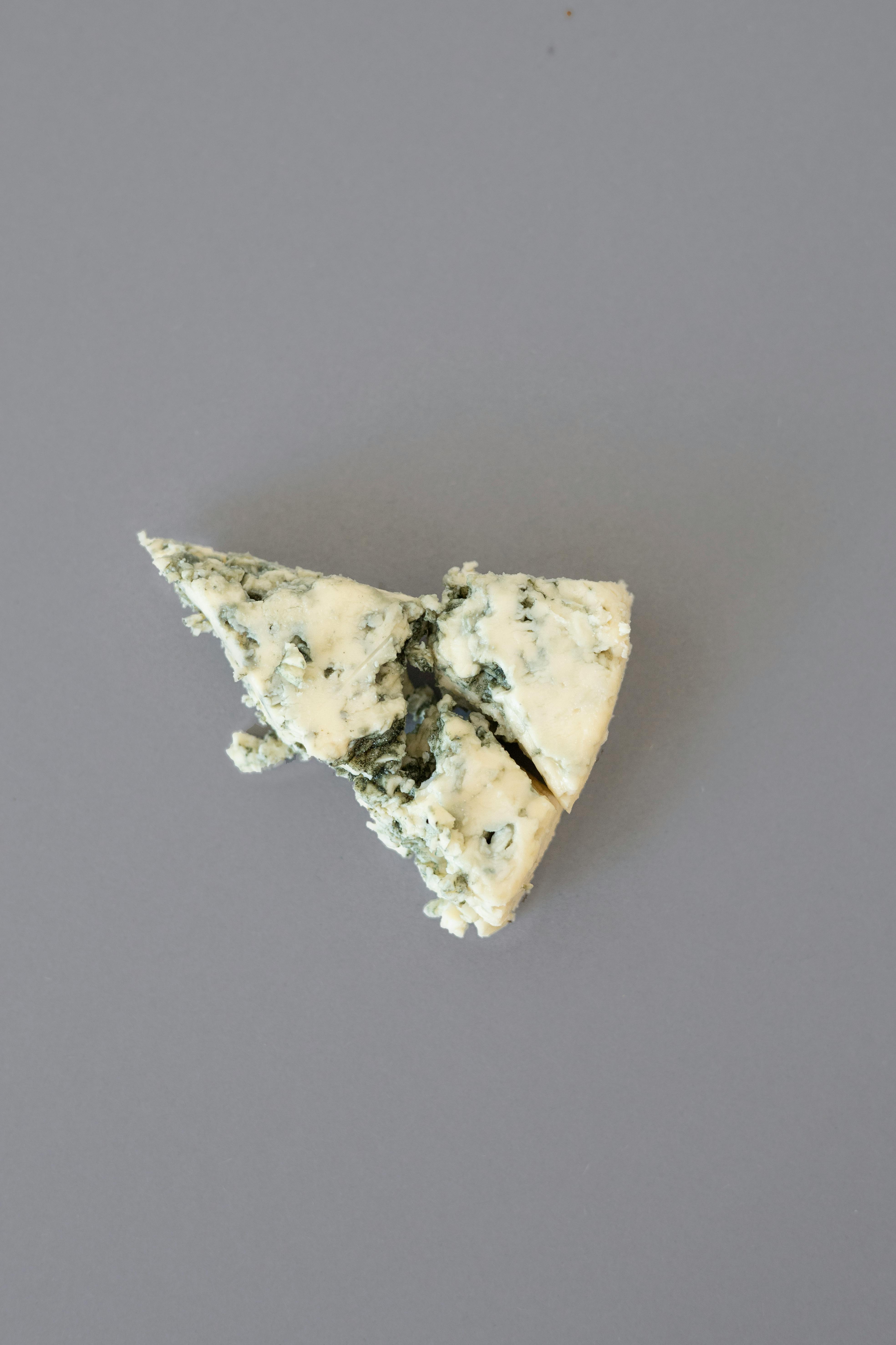 A slice of blue cheese on a gray background, captured in a flatlay style.