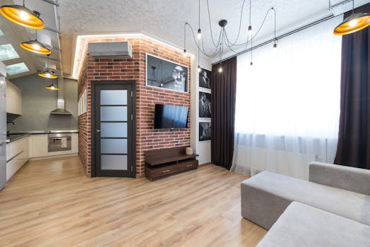 Sleek living room with brick wall, open kitchen, and contemporary decor.