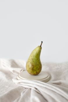 A minimalist still life photograph featuring a single pear on a neutral background