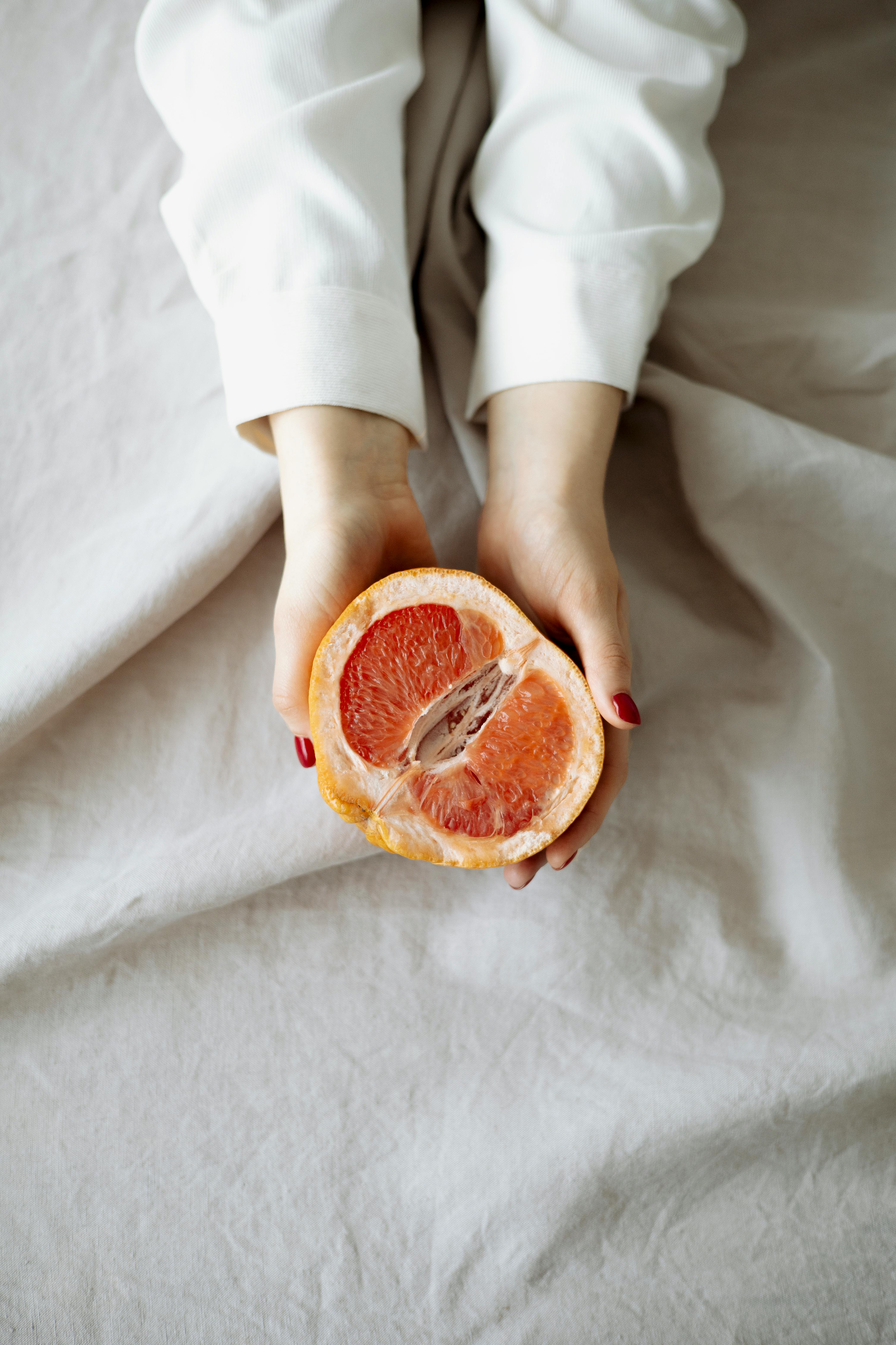 person holding sliced orange fruit