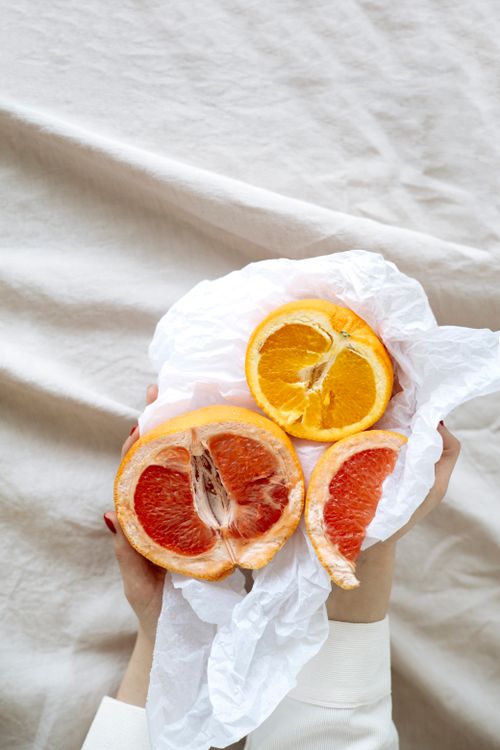 Free Citrus slices held over plain fabric, showcasing vibrant colors and freshness. Stock Photo