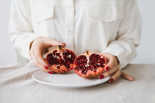 Close-Up Shot of a person Holding Slices of Pomegranate