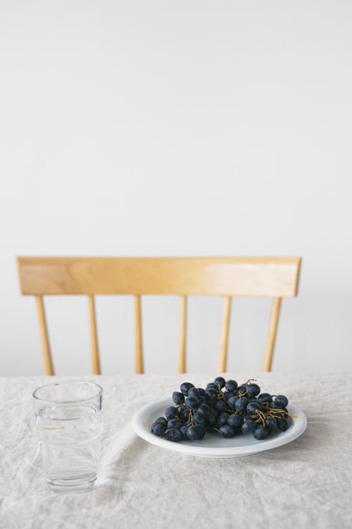 Free A simple and elegant table setup featuring a plate of fresh black grapes and glasses of water. Perfect for healthy dining. Stock Photo