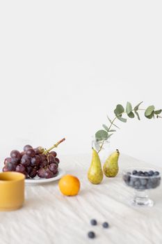 Minimalist still life of fresh fruits and leaves on a simple white background.