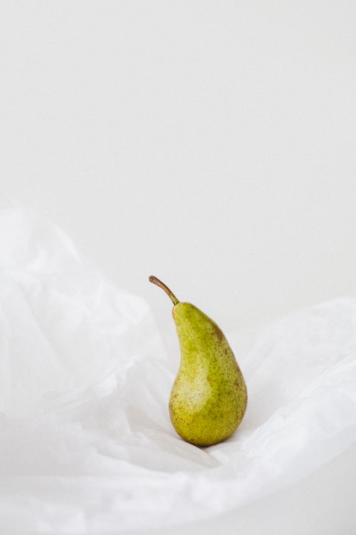 Free A minimalist still life featuring a fresh pear on a white background, highlighting simplicity. Stock Photo
