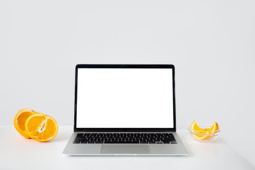Free Mockup of a laptop with orange slices, offering a fresh and minimalist design ideal for product presentations. Stock Photo