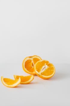 Minimalist still life of fresh orange slices on a plain white background.