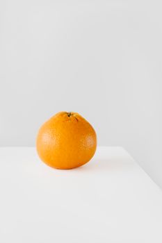 Simple minimalist photo of an orange on a white surface, perfect for food concepts.