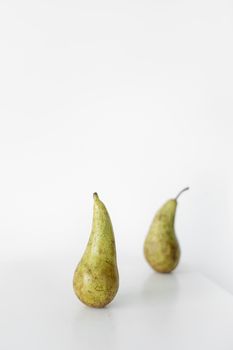 Simple and minimalist still life featuring two pears on a white background.