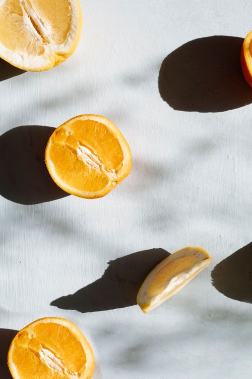 Free Top view of sliced oranges casting shadows on a white background in a minimalist style. Stock Photo