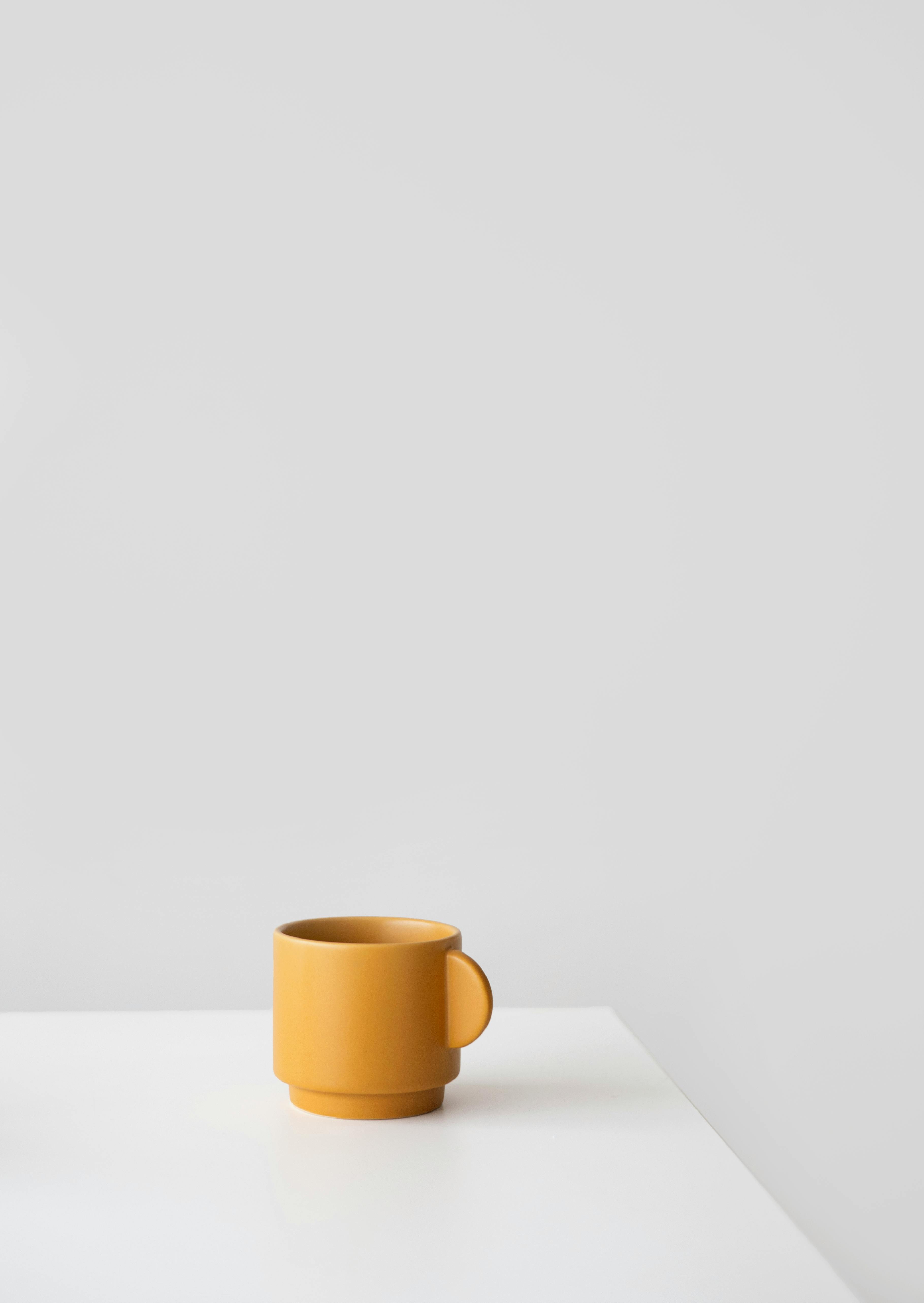 Simple yellow mug against a white background in a minimalist style.