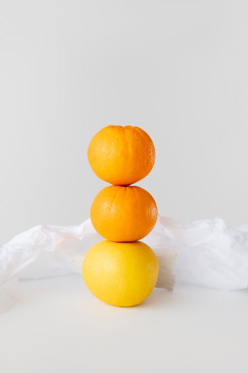 Free Minimalist still life of stacked citrus fruits on a plain white backdrop. Stock Photo