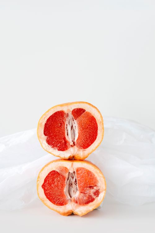 Free Vertical close-up of two grapefruit halves stacked with a soft background, highlighting vibrant citrus textures. Stock Photo