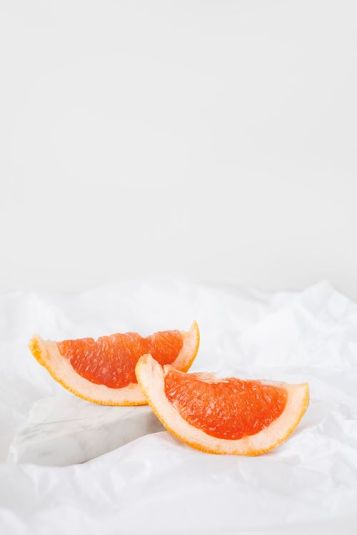 Free Two juicy grapefruit slices on a crisp white background, highlighting freshness and health. Stock Photo