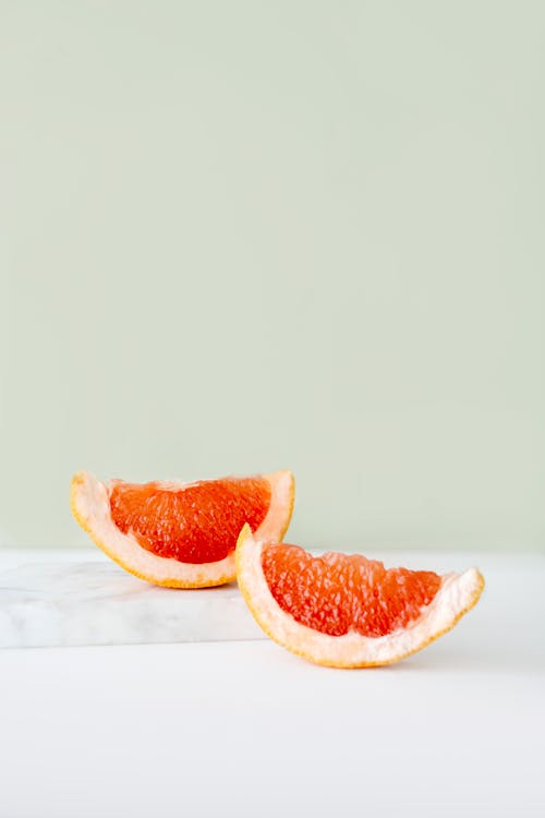 Free Slices of Grapefruit on White Surface Stock Photo